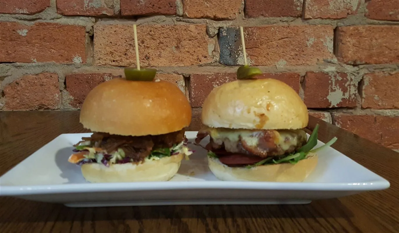 Two pulled-pork sliders on a white plate